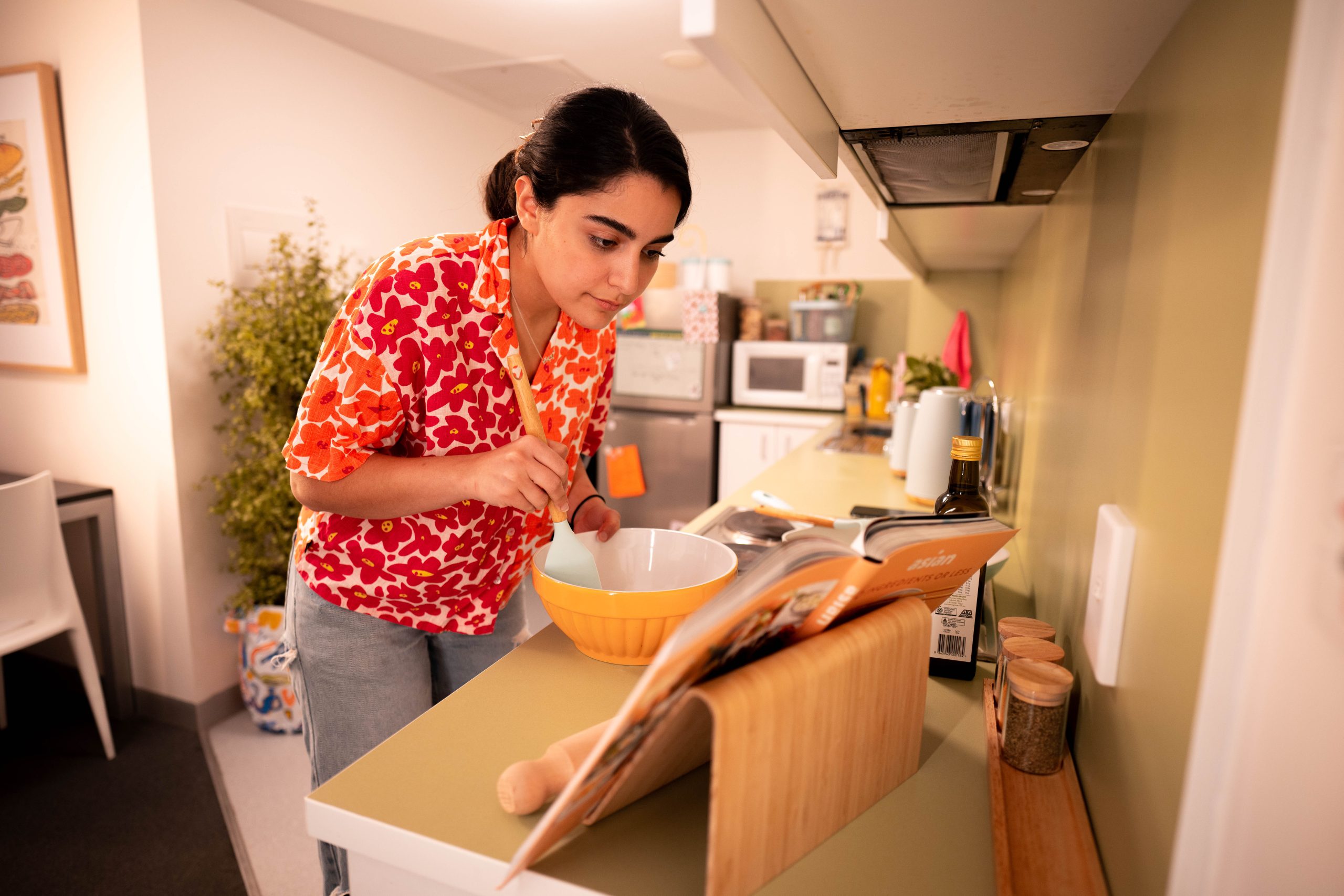 Student cooking in the kitchen of their large studio apartment