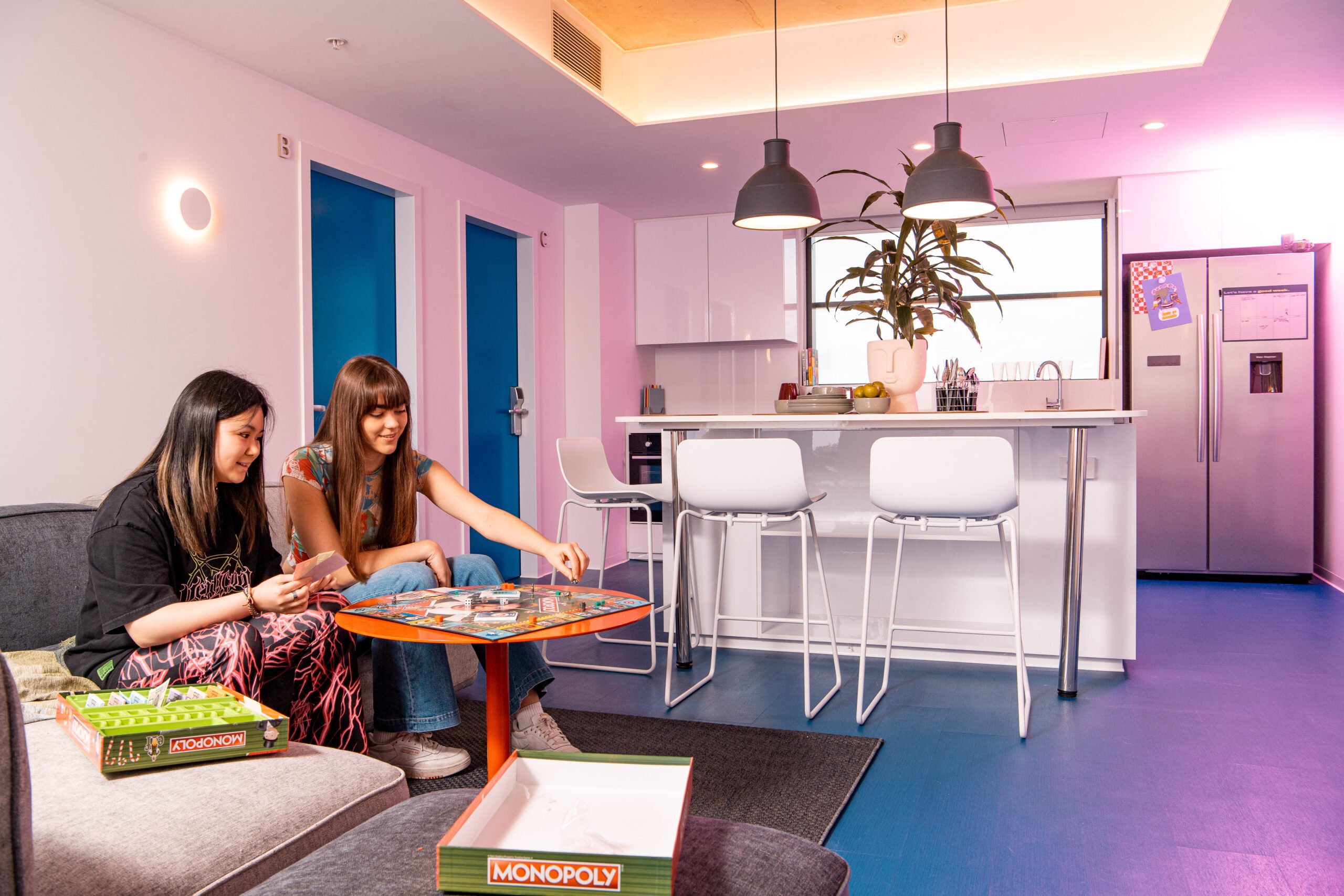 Residents sitting in front of table in living area at Scape Carlton student accommodation.
