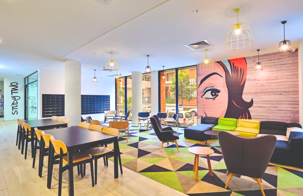 A vibrant student common room features a pop art mural, colourful seating, and modern tables.